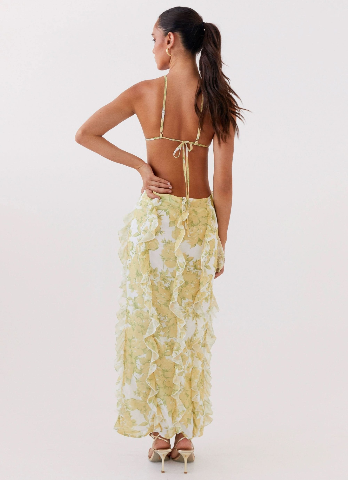 Yellow floral maxi dress showing tied back closure and cascading ruffle details