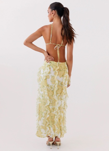 Yellow floral maxi dress showing tied back closure and cascading ruffle details