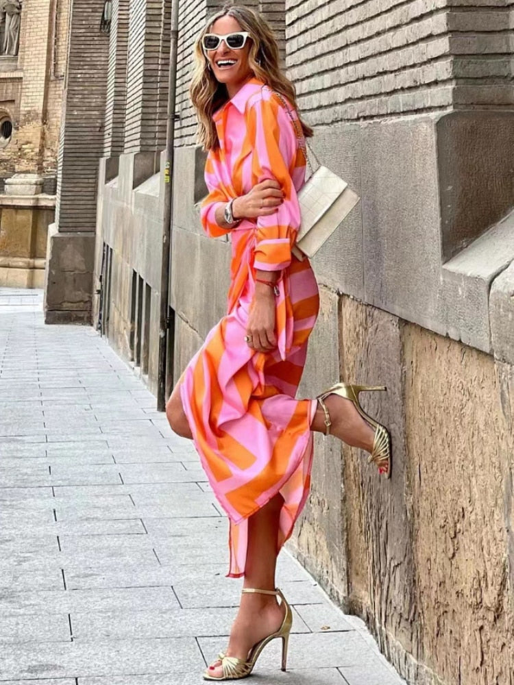 Side view of pink and orange striped wrap midi dress with asymmetrical ruched skirt