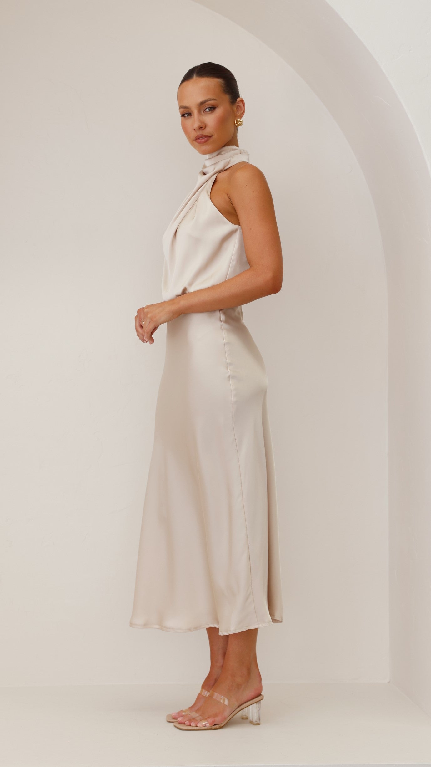 Side view of ivory draped midi dress with sleeveless cut and midi length