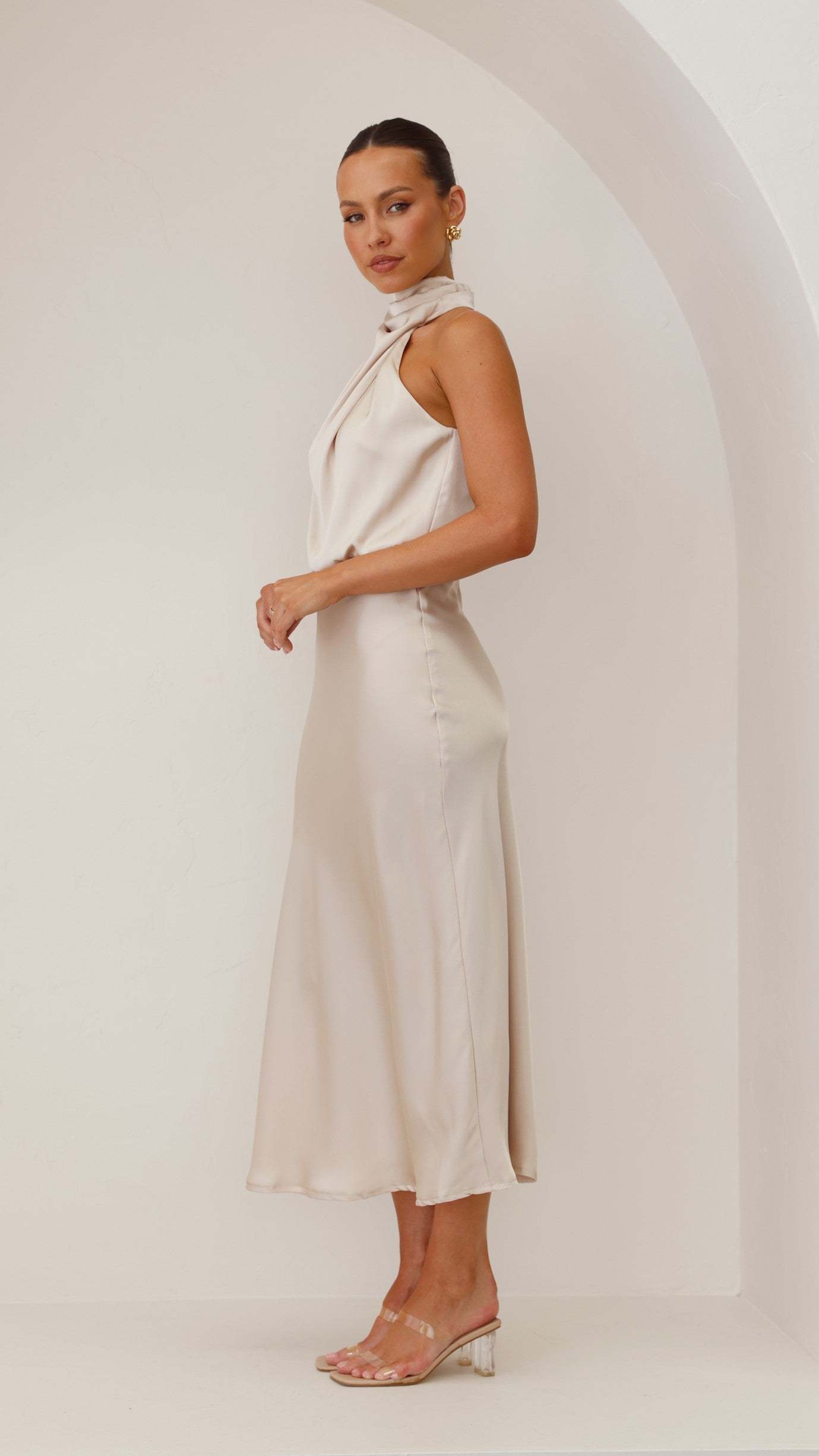 Side view of ivory draped midi dress with sleeveless cut and midi length