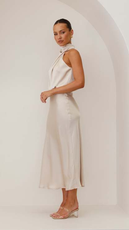 Side view of ivory draped midi dress with sleeveless cut and midi length