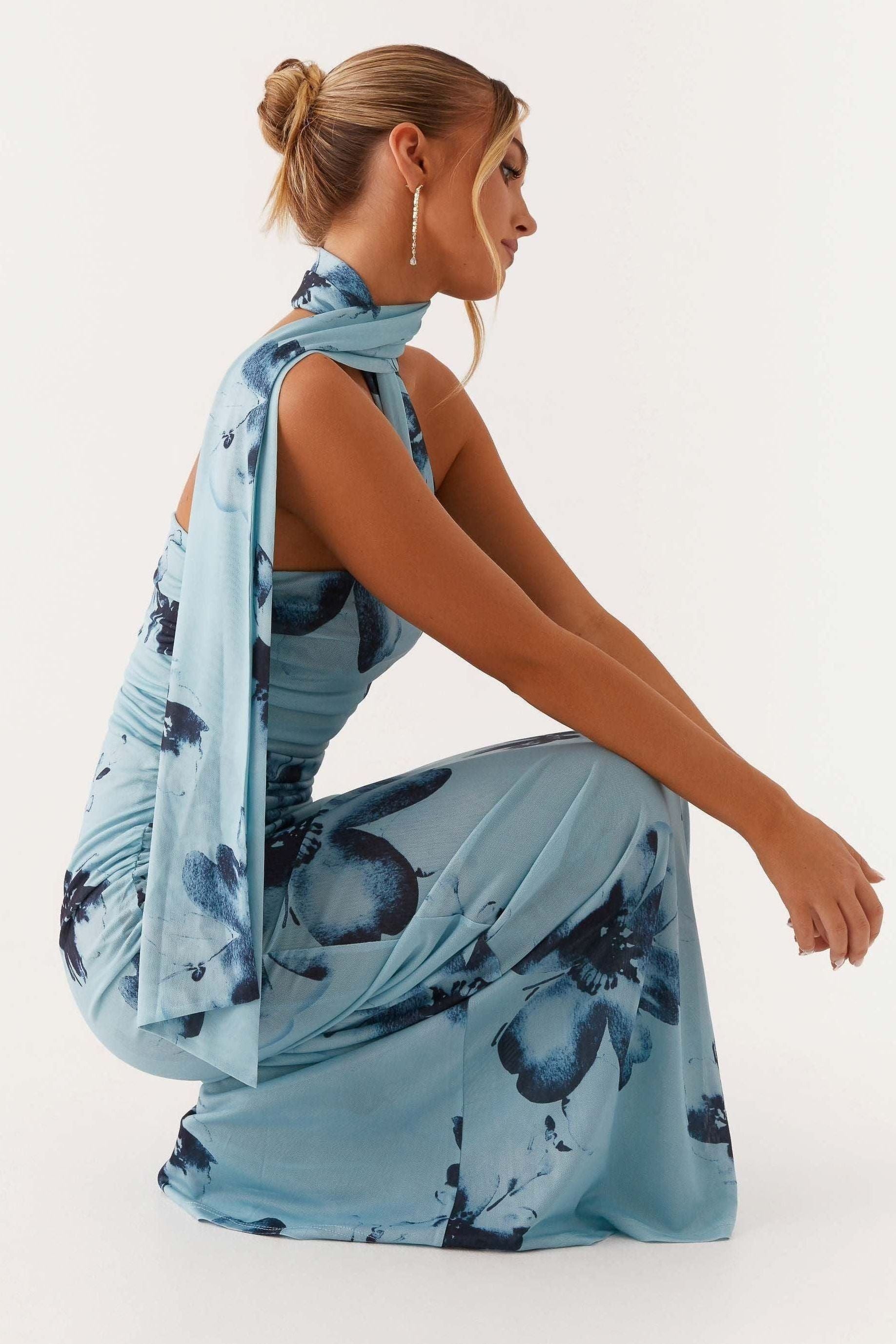 Back view of blue floral maxi dress showing halter tie and ruched side seams