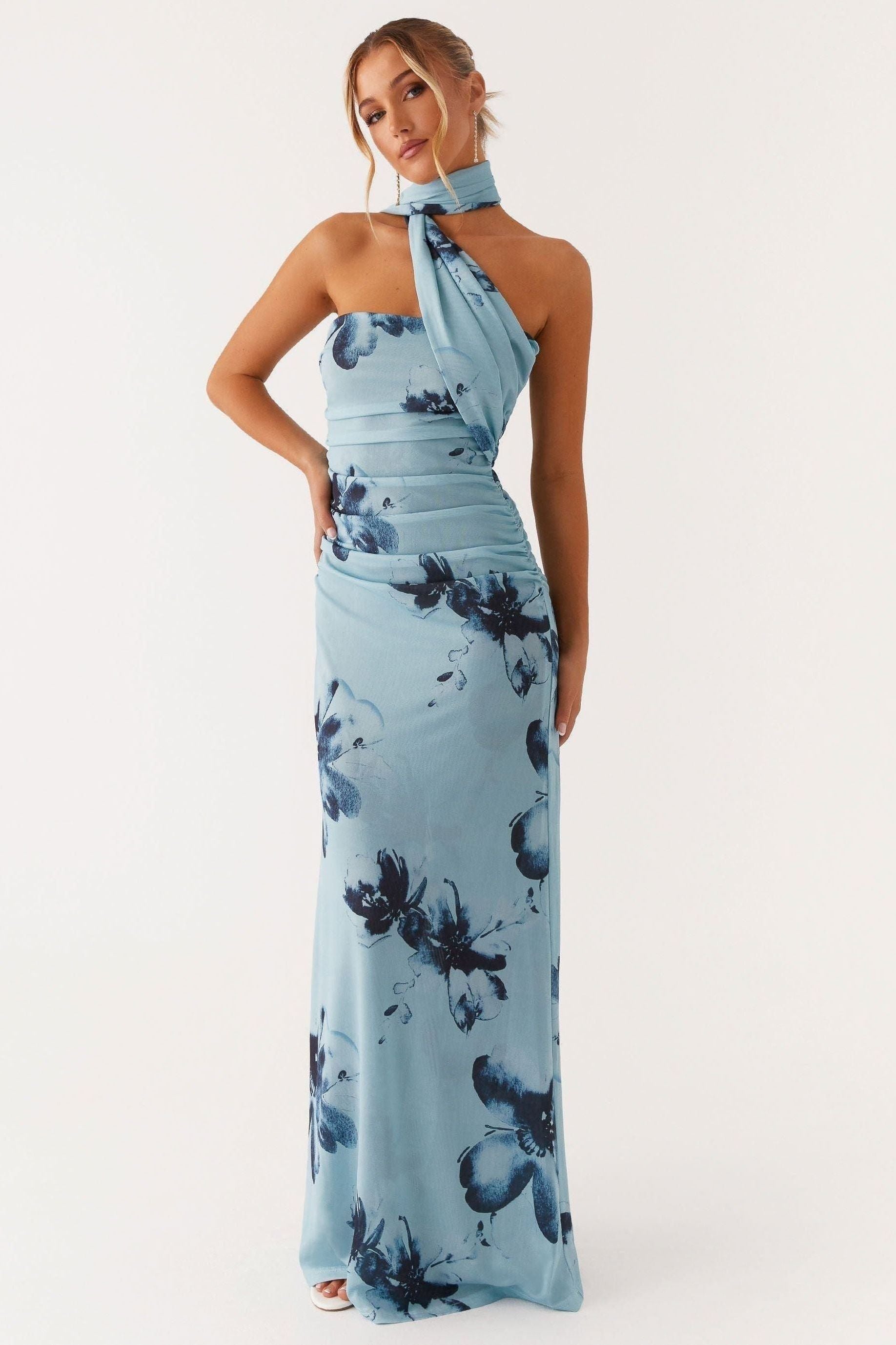 Blue halter maxi dress with navy floral print, ruched waist, and flowing skirt