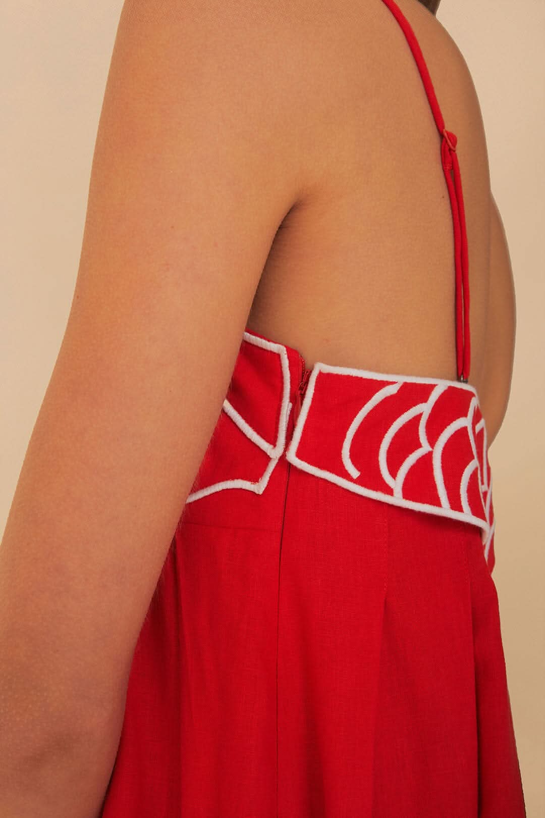 Close-up of red maxi dress back featuring white embroidered fish scales