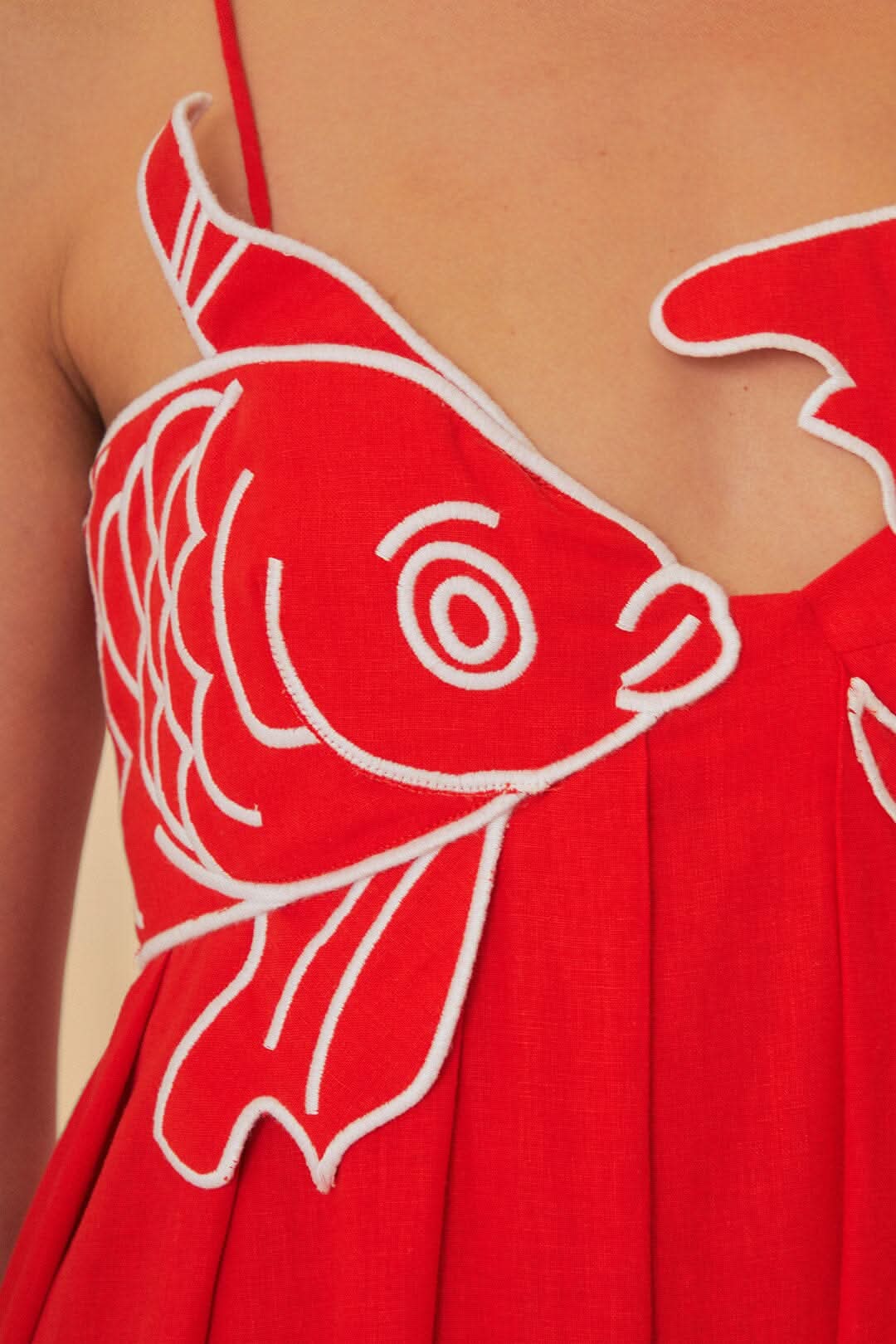 Detailed view of white fish embroidery on red maxi dress bodice