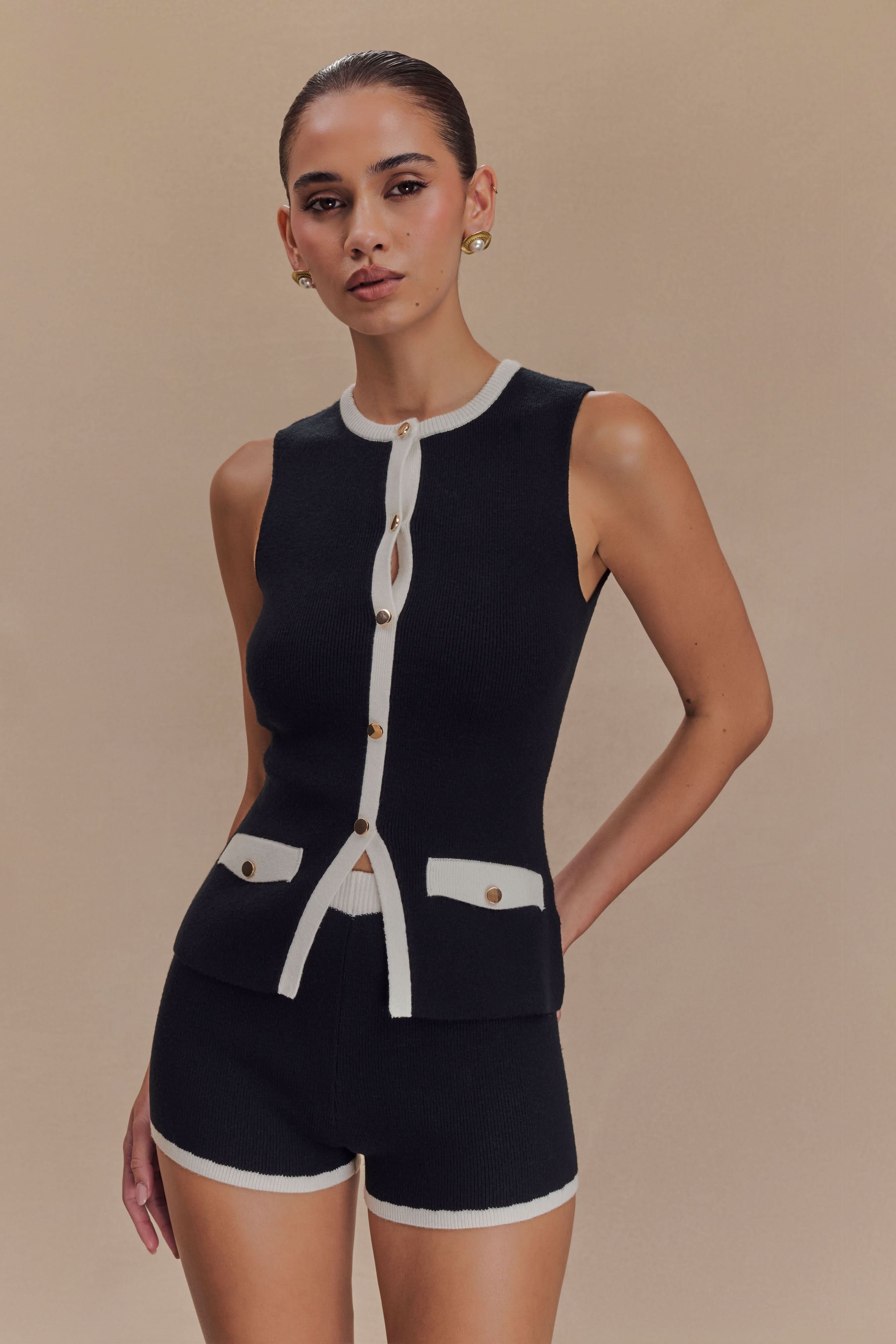 Black sleeveless knit vest with white contrast trim and button front closure