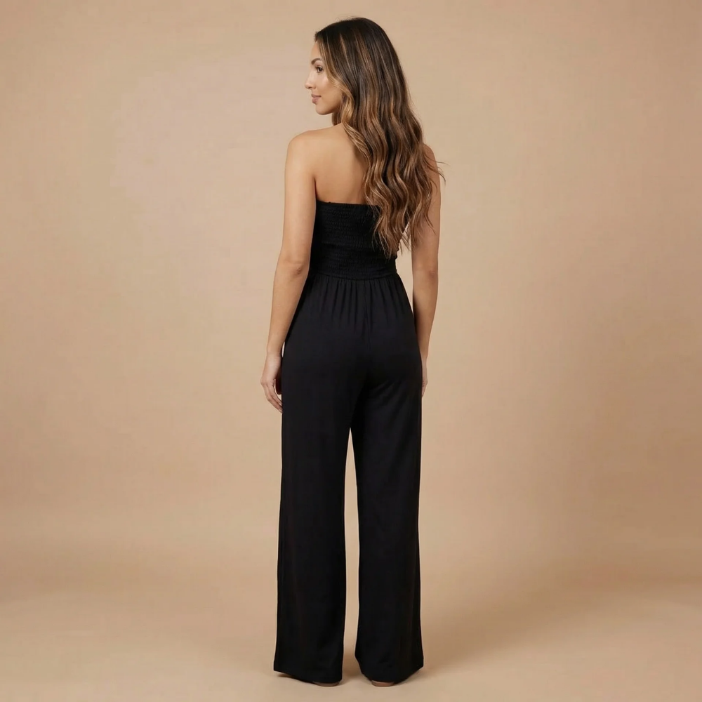 Back view of black strapless smocked jumpsuit with flowing wide-leg silhouette