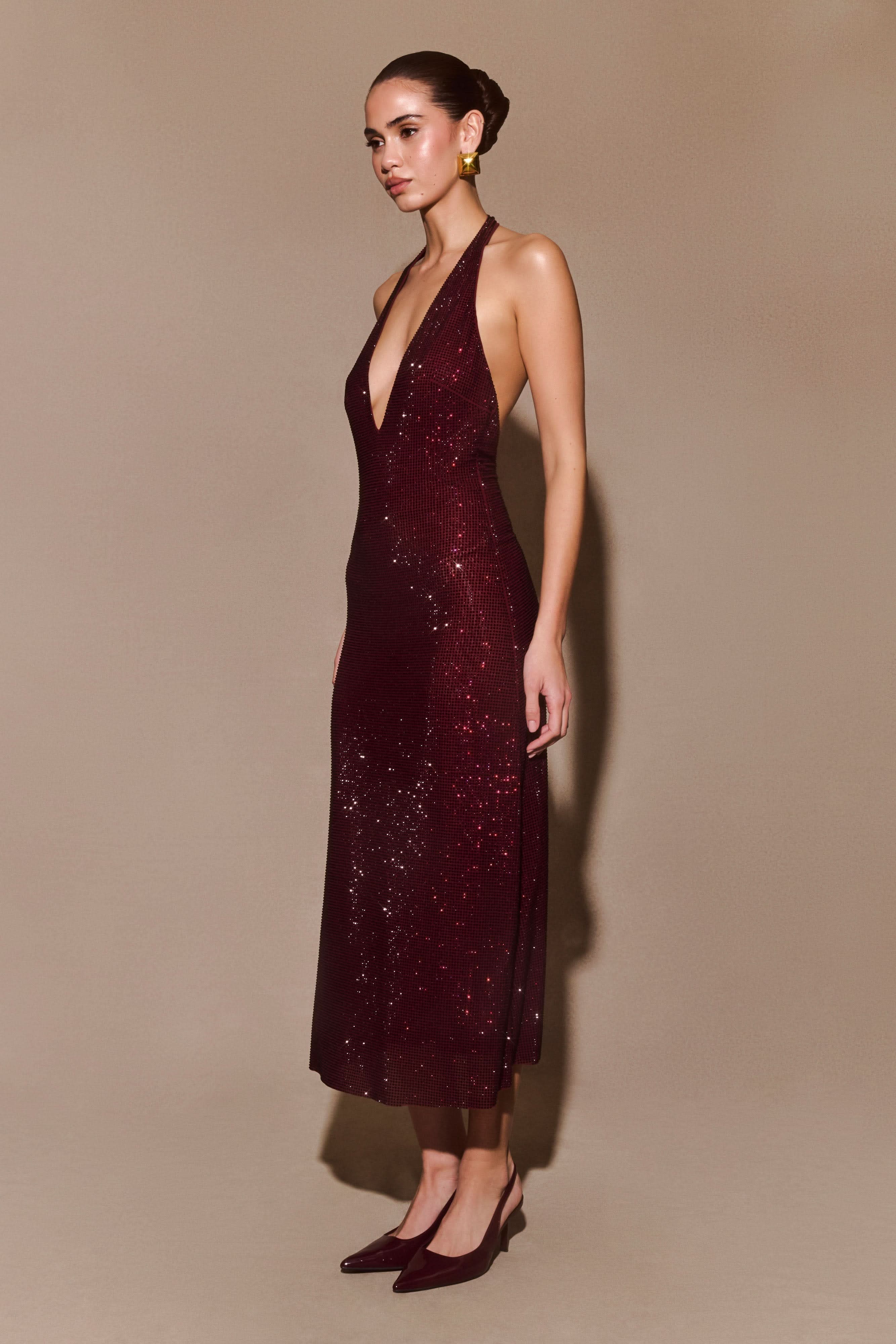 Side view of burgundy sequined halter dress with backless design