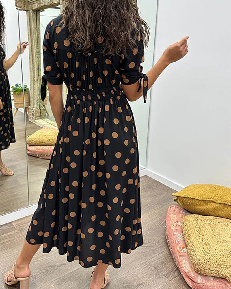 Black wrap midi dress with tan polka dots, back view with tied sleeves