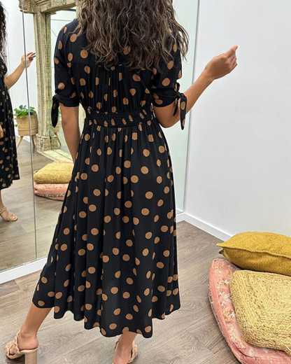 Black wrap midi dress with tan polka dots, back view with tied sleeves