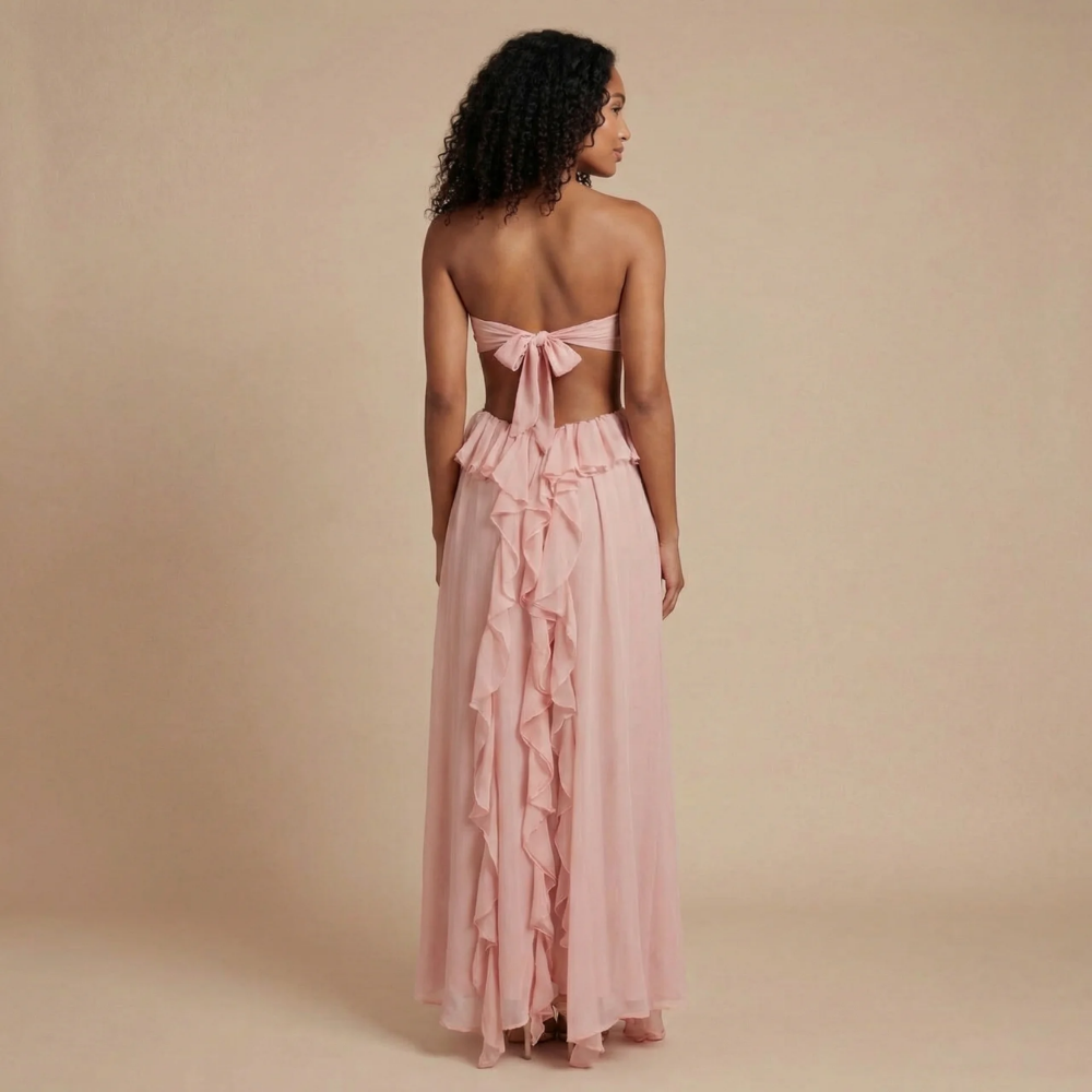Back view of blush pink maxi dress showing tie-back bow closure and flowing ruffle trim