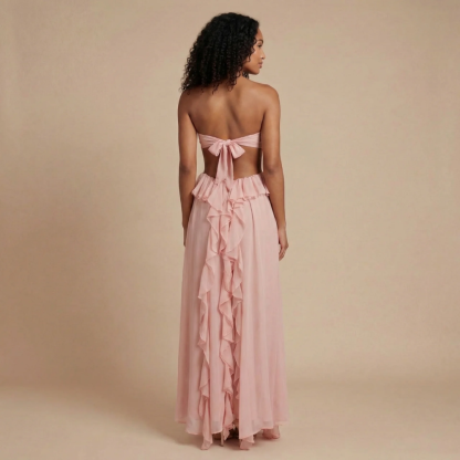 Back view of blush pink maxi dress showing tie-back bow closure and flowing ruffle trim