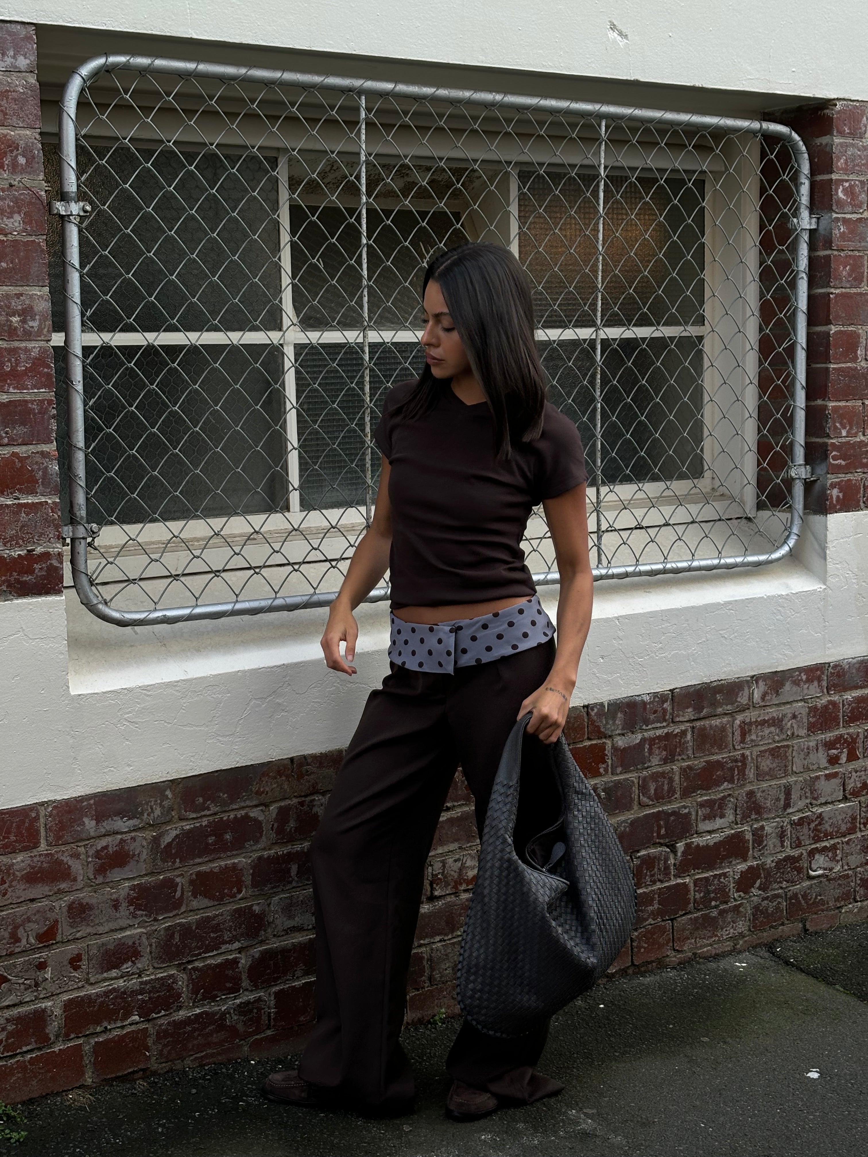 Black tailored pants with sage polka dot waistband, standing pose outdoor
