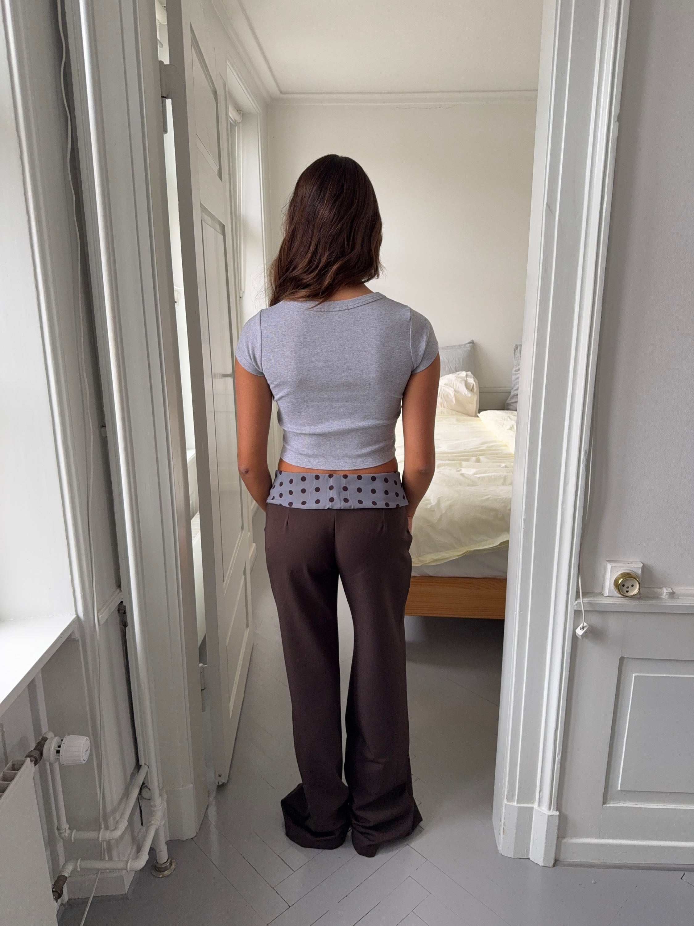 Black tailored pants with sage polka dot waistband, rear view flat lay
