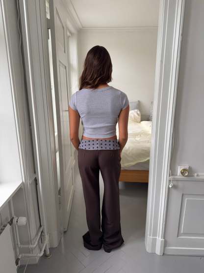 Black tailored pants with sage polka dot waistband, rear view flat lay