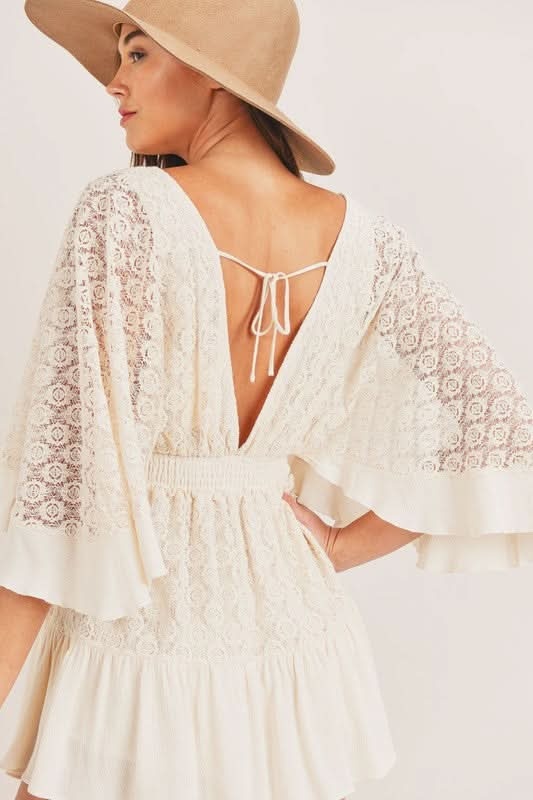 Back view of cream lace romper with open tie back and flutter sleeves
