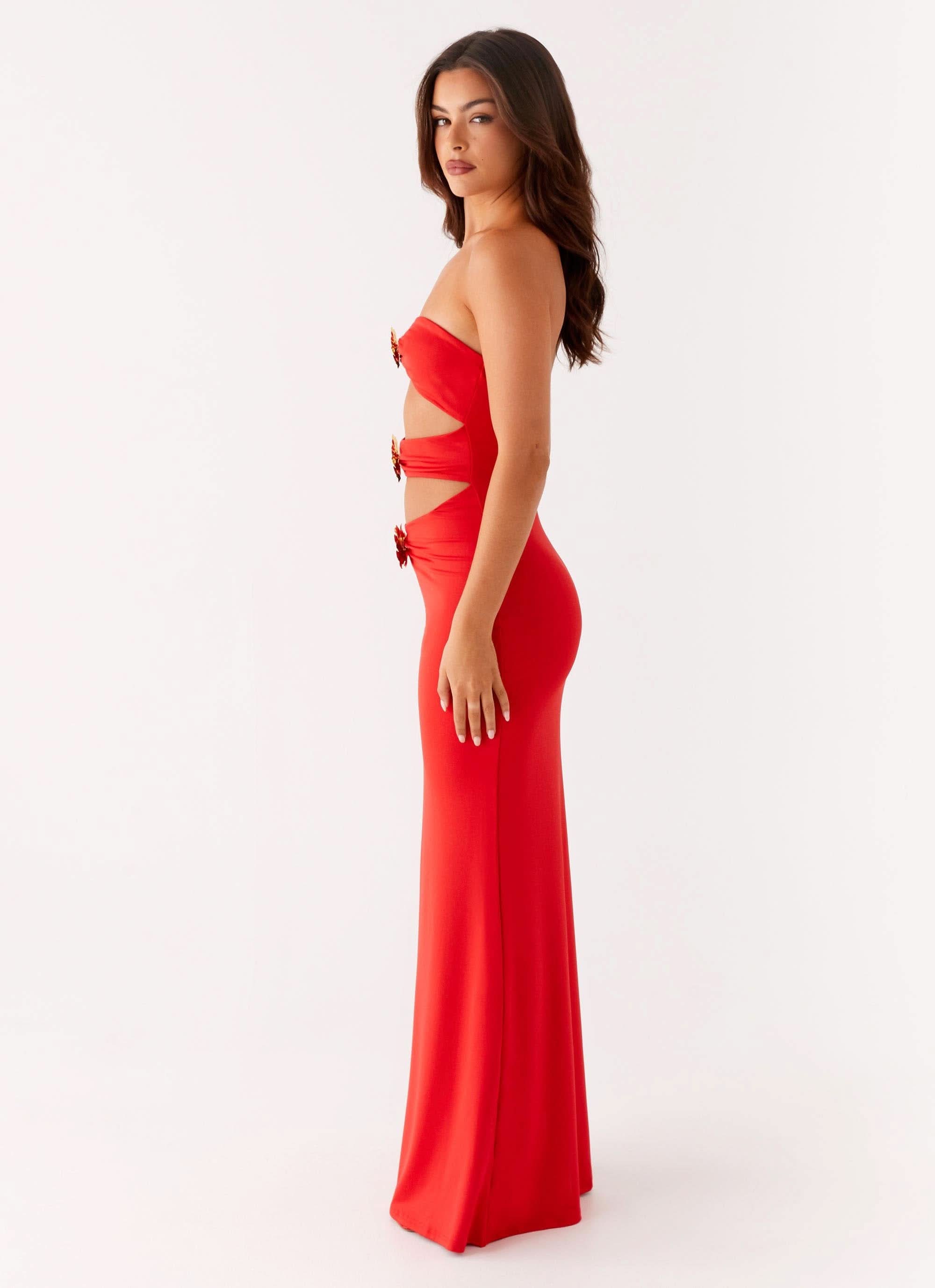 Side view of red cutout maxi dress with side slit and gold buckle accents