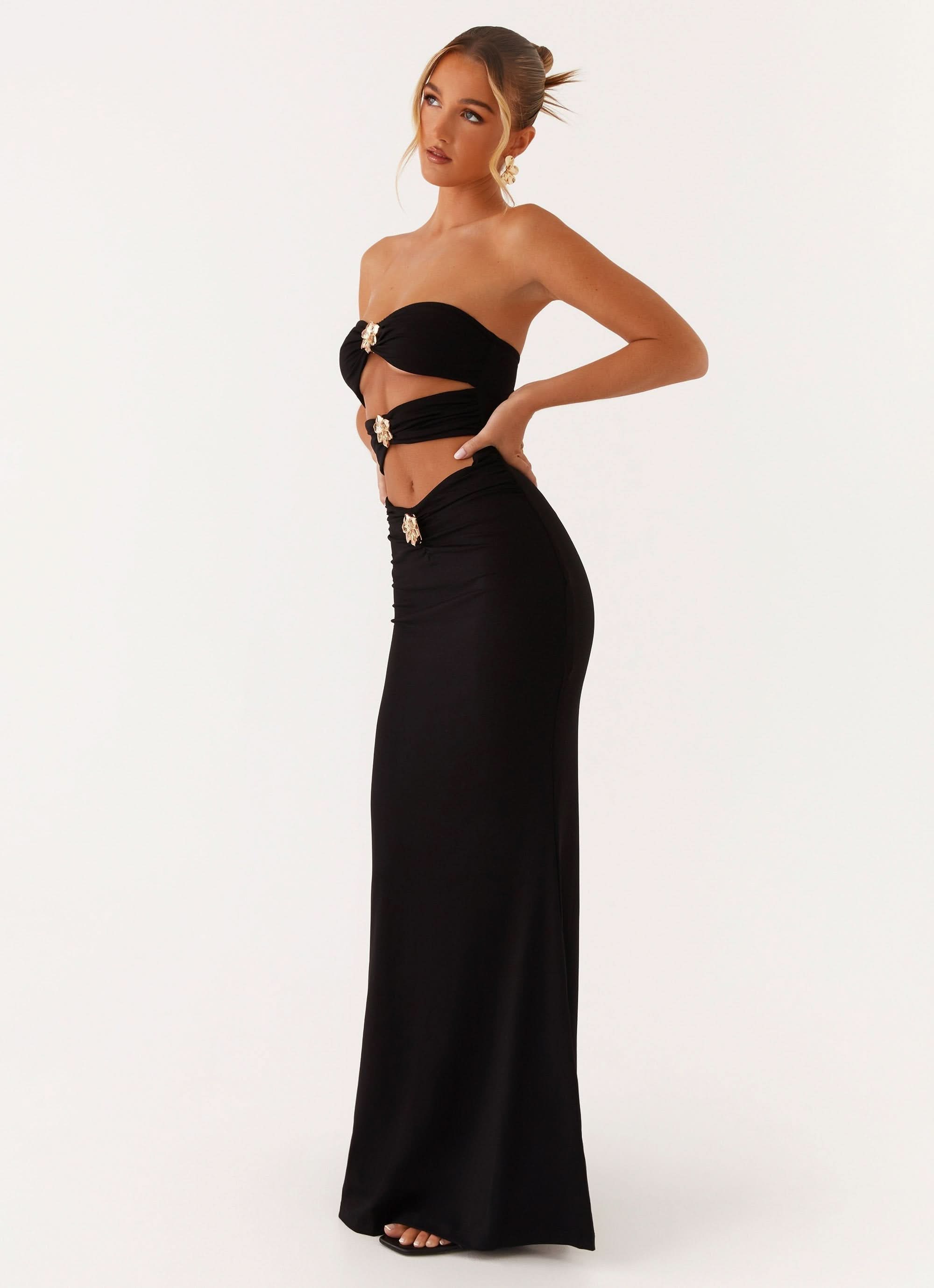 Side view of black cutout maxi dress with gold buckle accents and side slit
