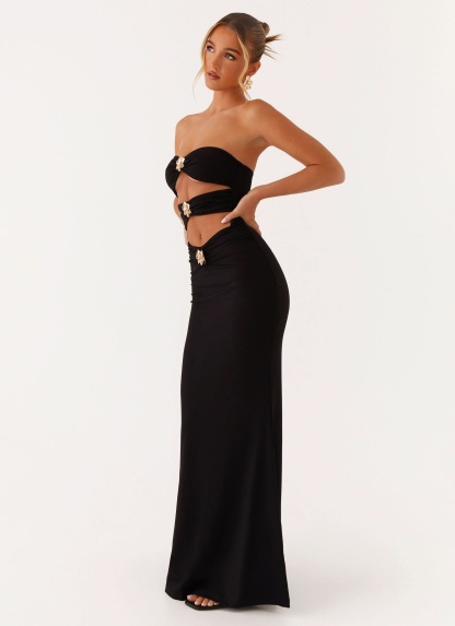 Side view of black cutout maxi dress with gold buckle accents and side slit