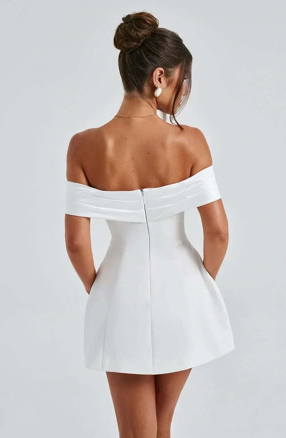 Rear detail of white mini dress showing center back zipper and off-shoulder neckline