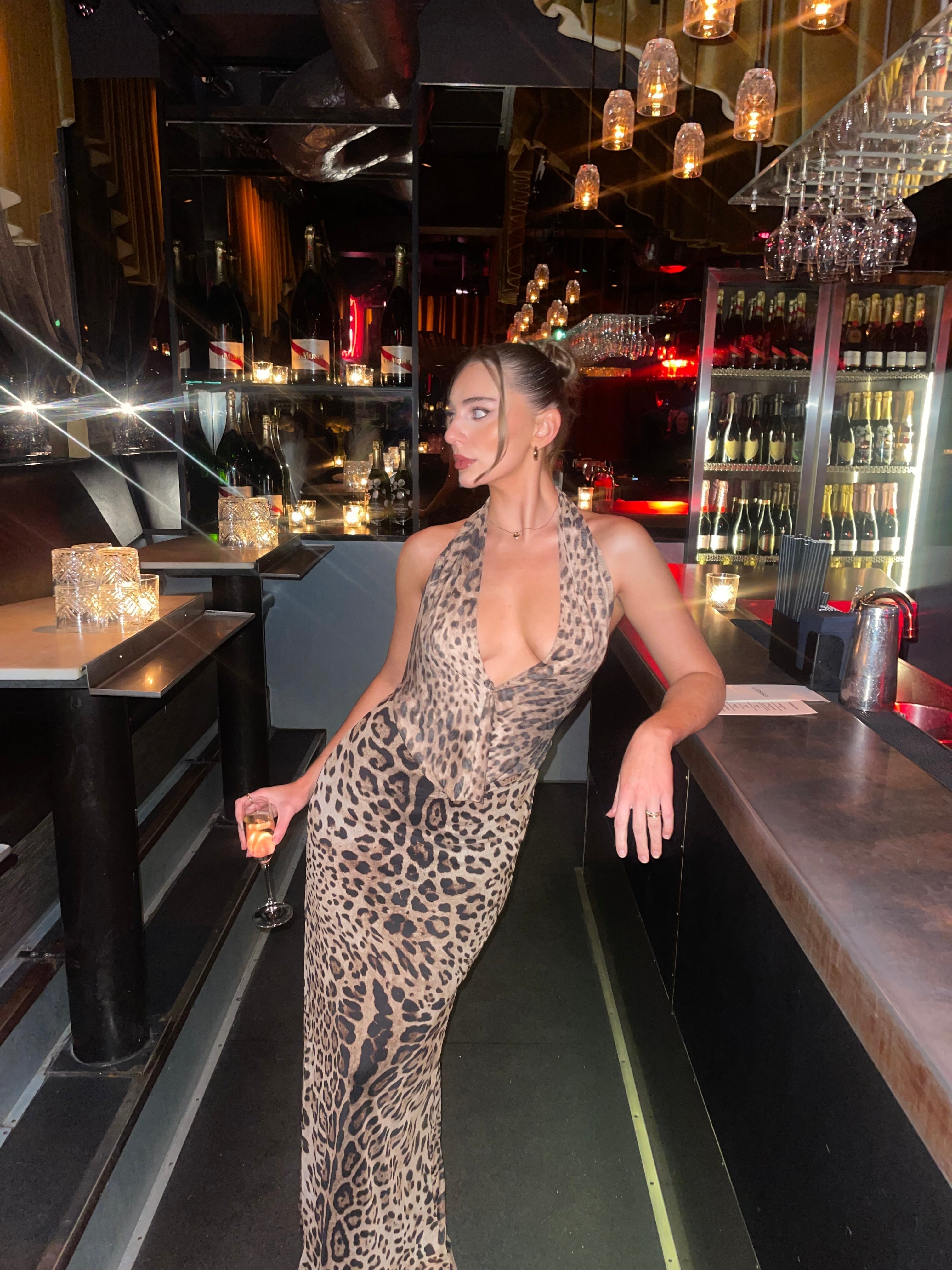 Leopard print halter maxi dress with deep V-neckline at bar