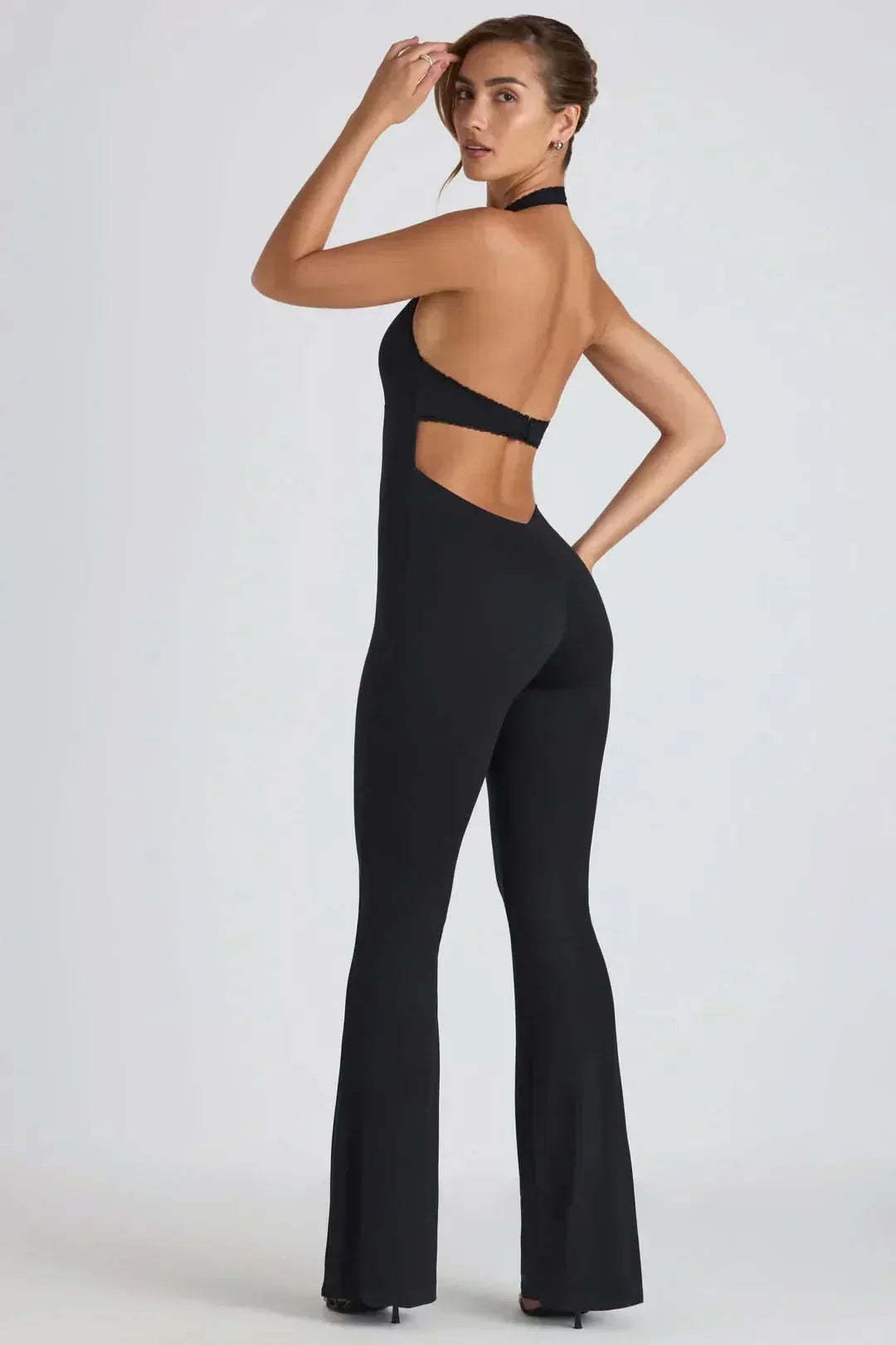 Back view of black backless jumpsuit showing open back and flared silhouette