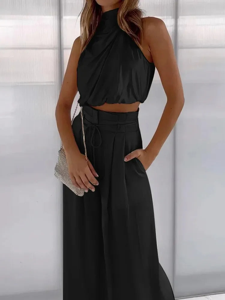 Black draped halter crop top with pleated high-waisted wide pants and tie waist