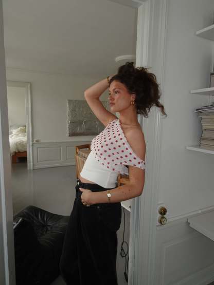 Red polka dot draped crop top with white ribbed band, side view