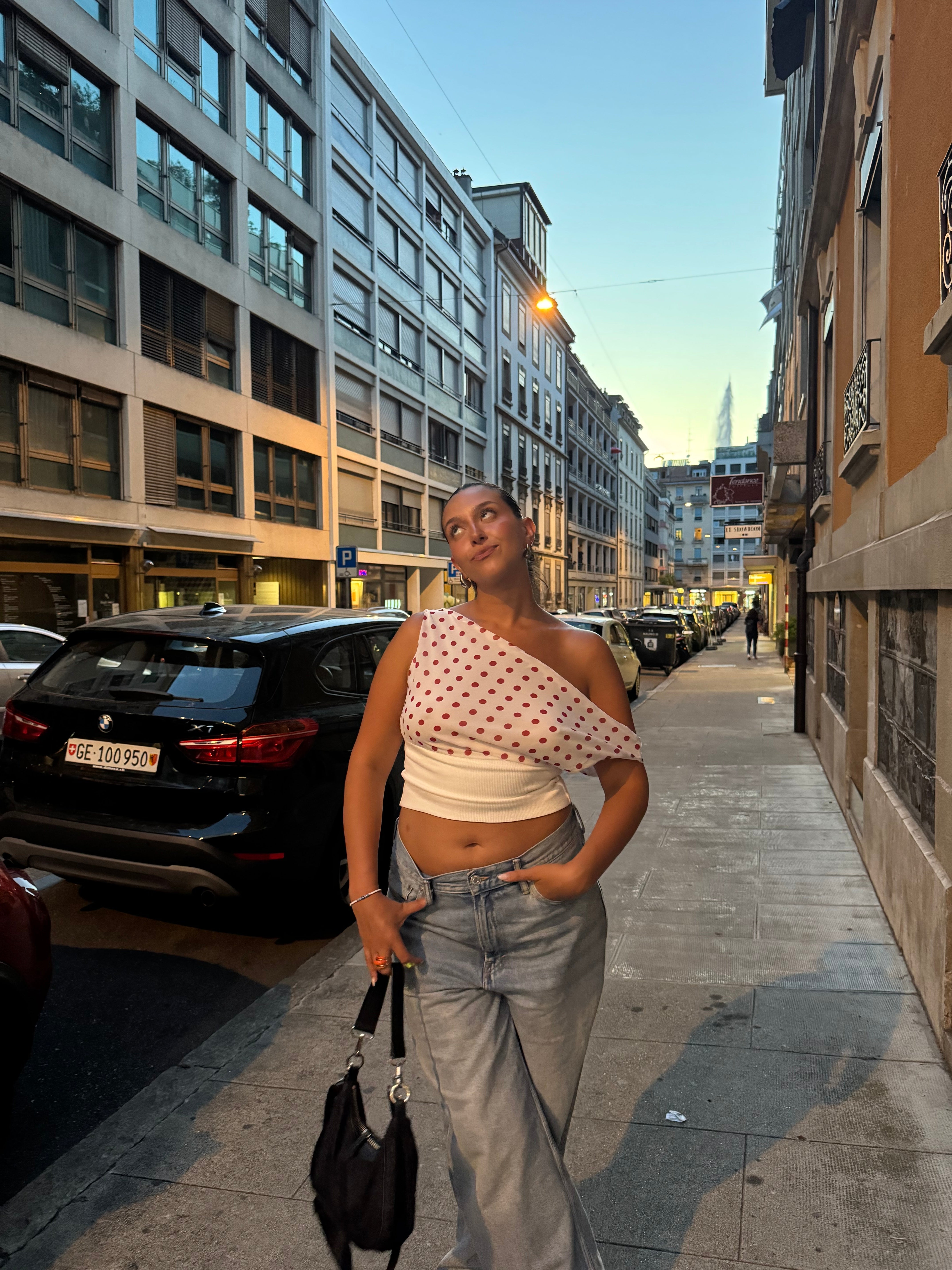 Polka dot draped crop top worn with light wash jeans on urban street