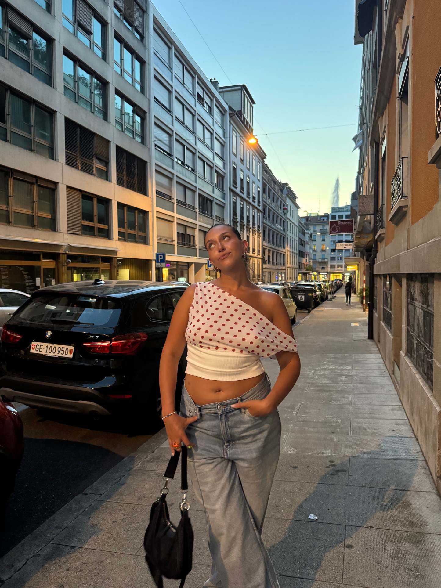 Polka dot draped crop top worn with light wash jeans on urban street