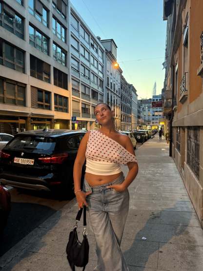 Polka dot draped crop top worn with light wash jeans on urban street