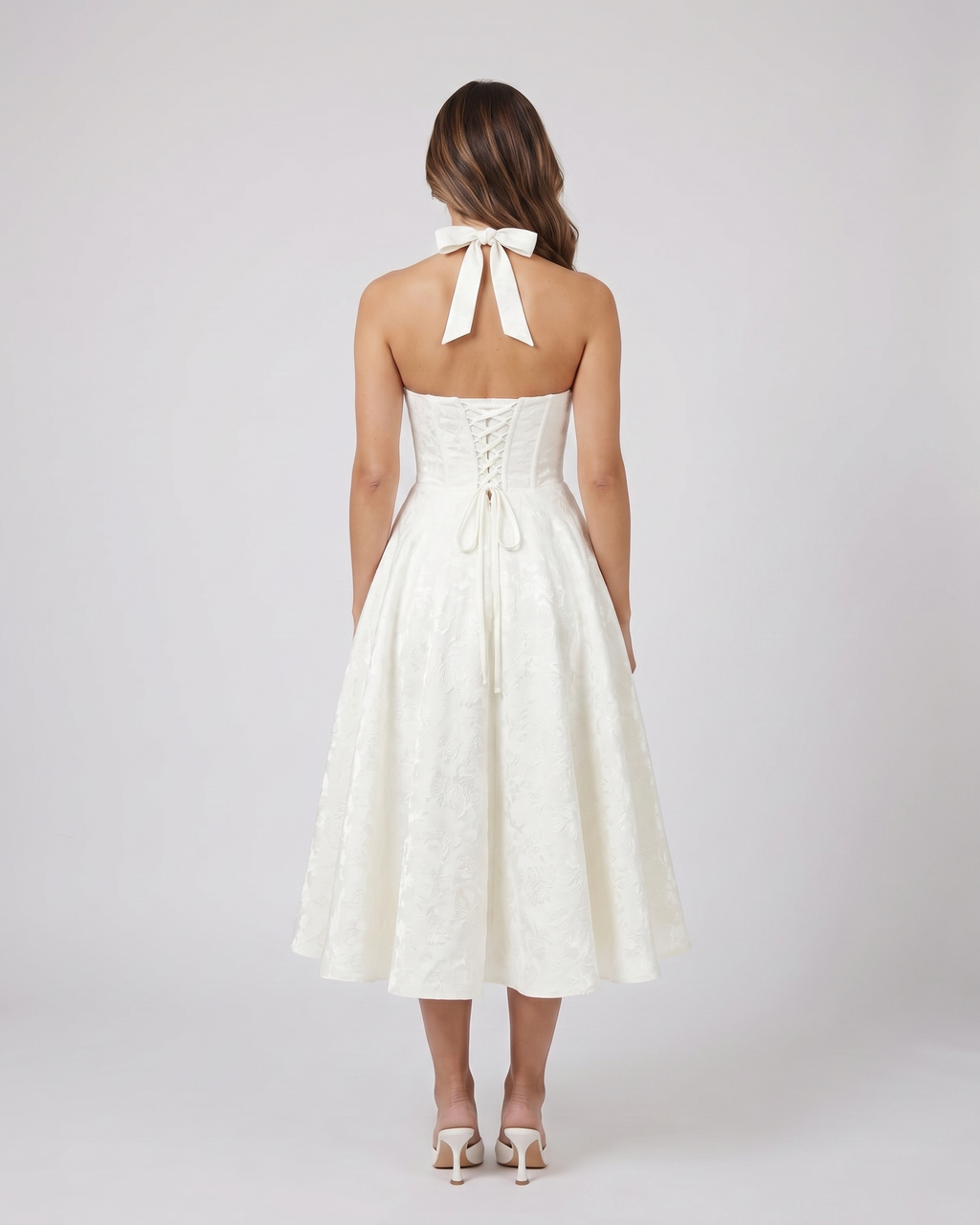 Back view of ivory floral jacquard halter midi dress showing lace-up corset back with halter tie-back forming a bow