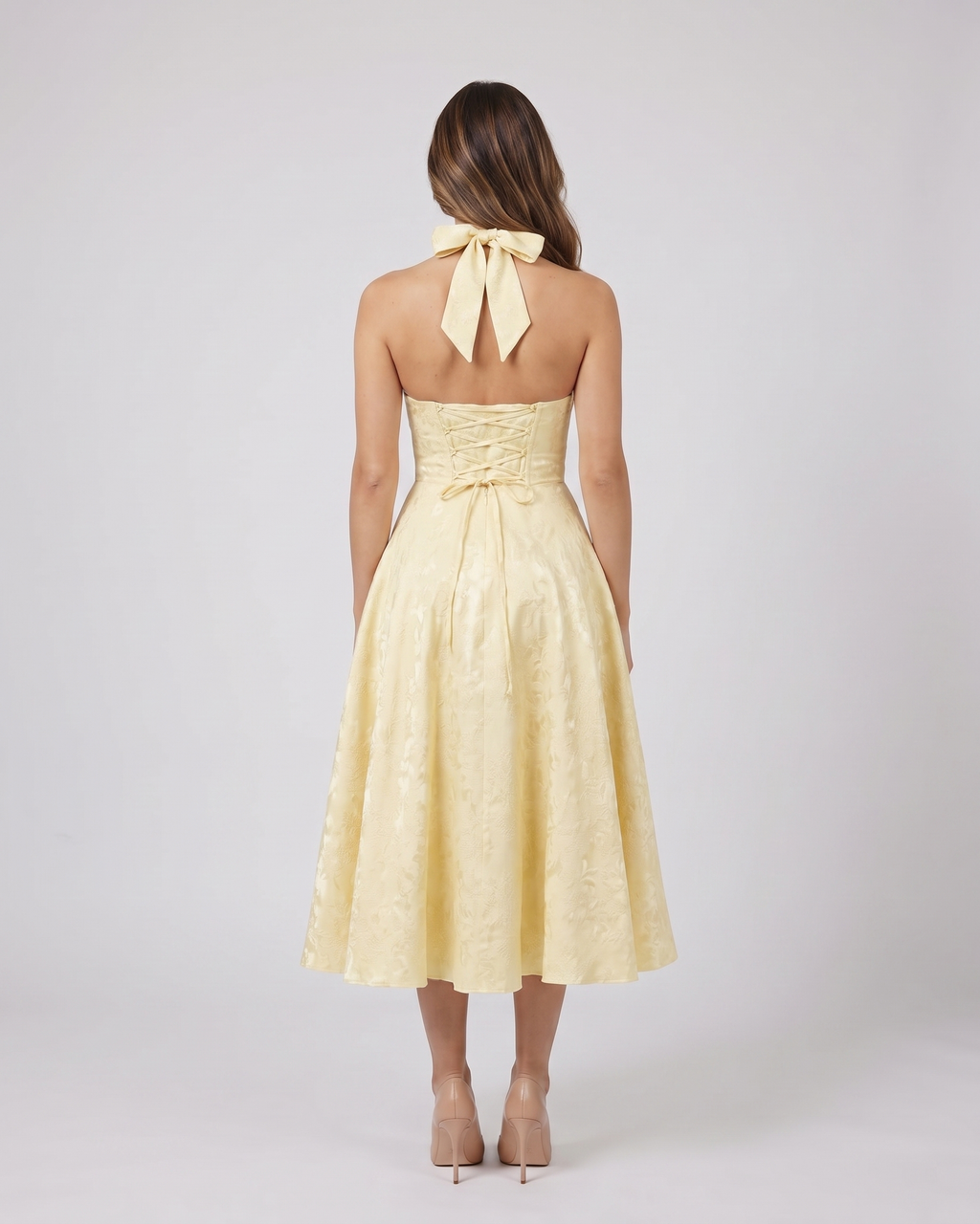 Back view of yellow floral jacquard halter midi dress showing lace-up corset back with halter tie-back forming a bow