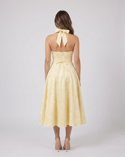 Back view of yellow floral jacquard halter midi dress showing lace-up corset back with halter tie-back forming a bow