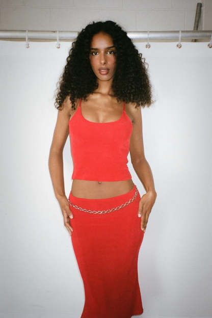 Red ribbed crop top with chain belt detail on matching midi skirt
