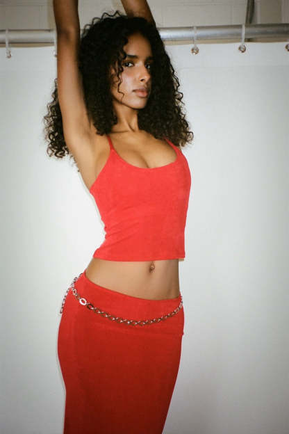 Side profile of red ribbed crop camisole with chain waist detail on midi skirt