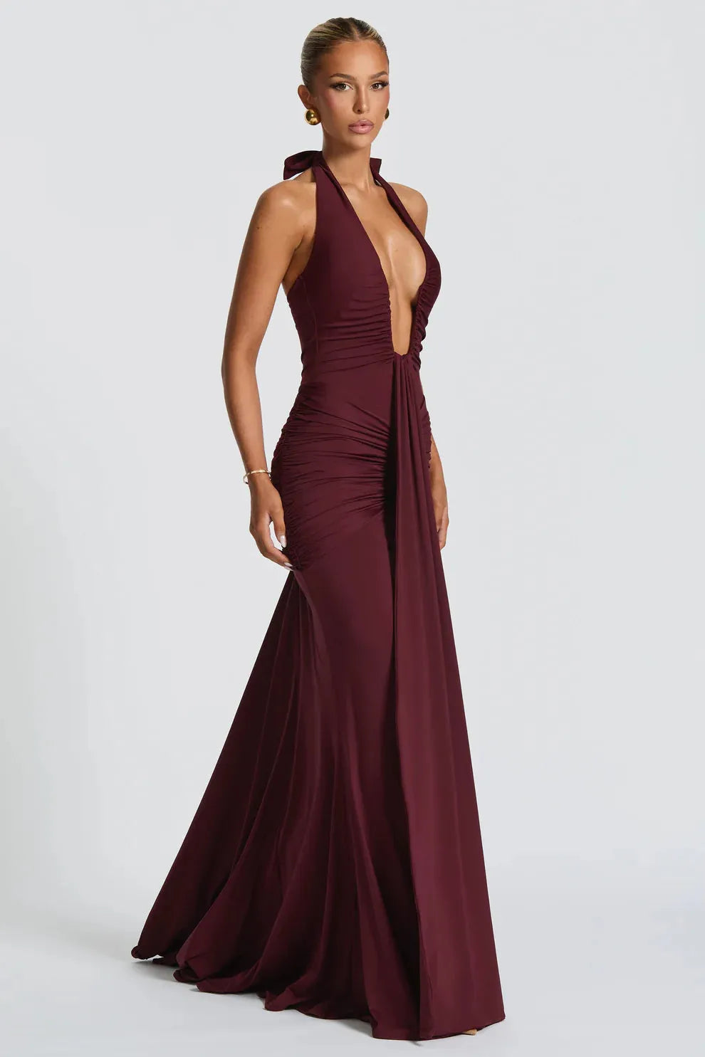 Side view of burgundy halter ruched maxi dress with fitted bodice