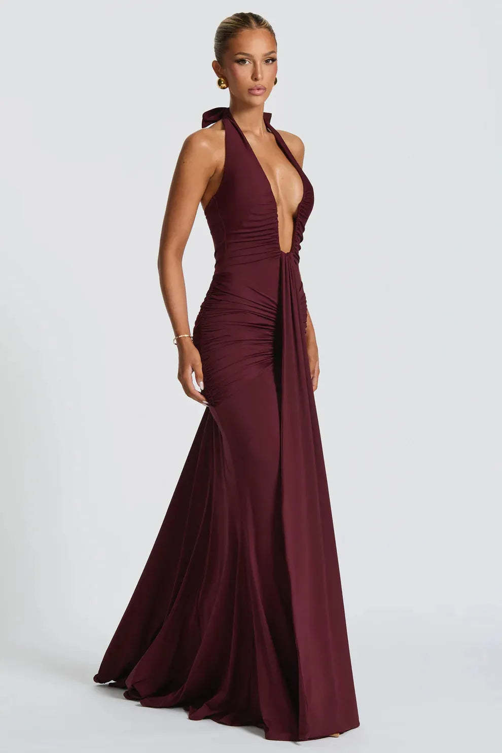 Side view of burgundy halter ruched maxi dress with fitted bodice