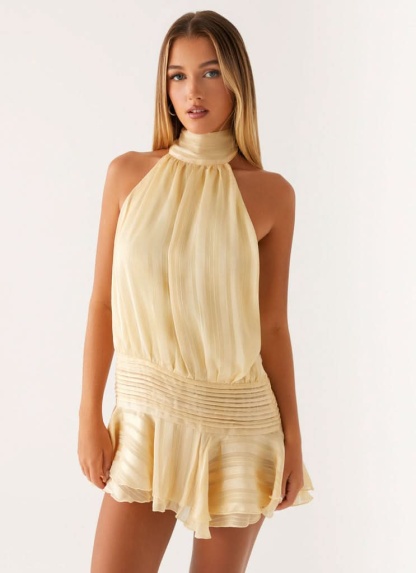 Cream pleated halter mini dress with cinched waist and layered ruffle skirt