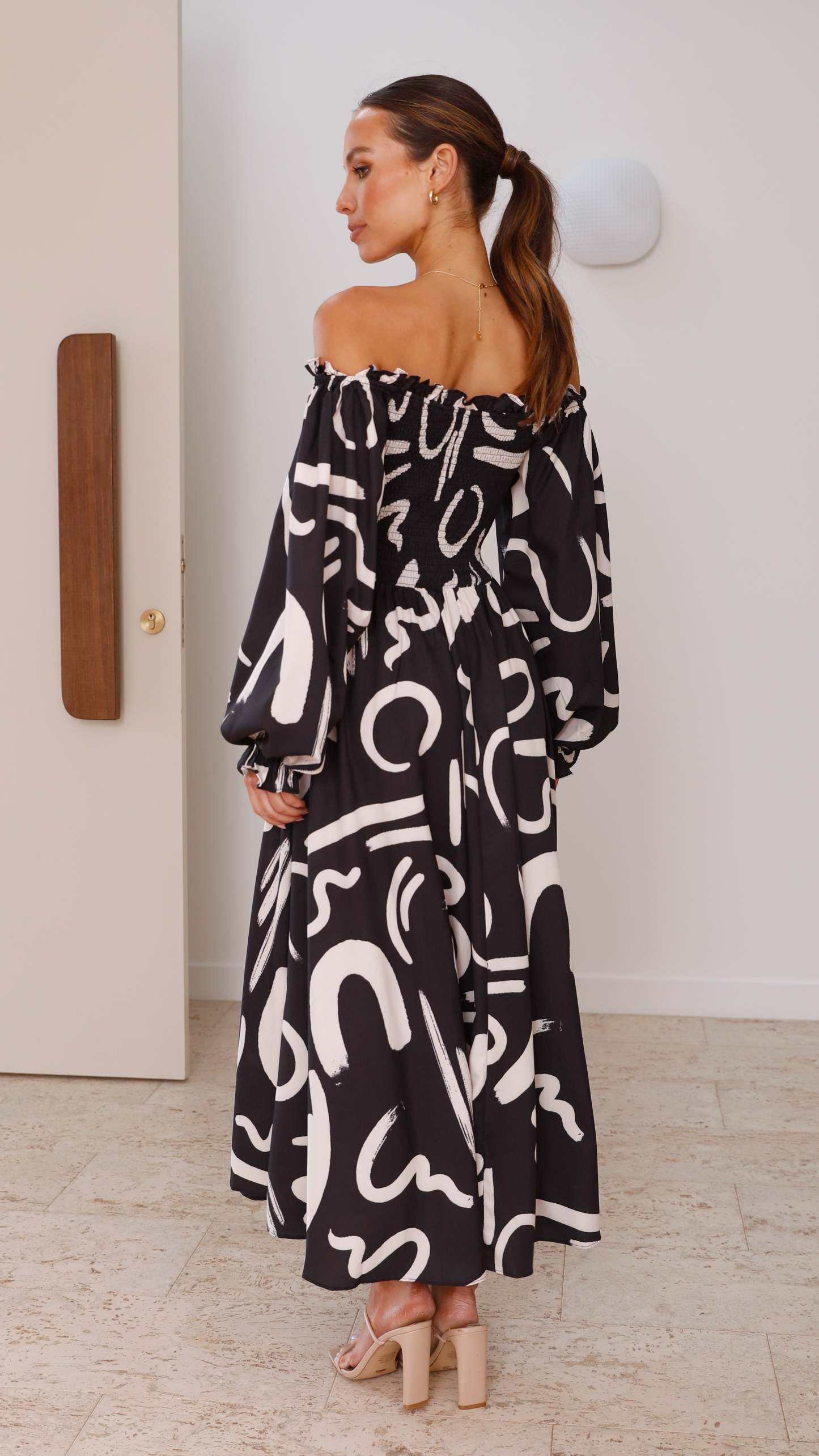 Back view of black abstract print maxi dress with puffed sleeves and flowing skirt