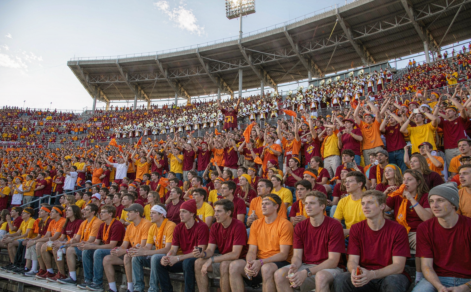 College football student section packed with fans in plain school-color jerseys on a fall Saturday
