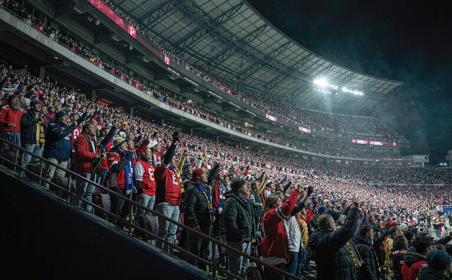Packed American football stadium crowd of fans in plain team-color jerseys
