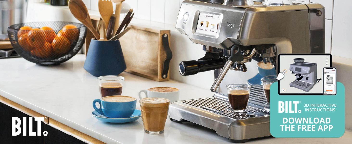 Máquina de café espresso en la encimera de la cocina con tazas de café, naranjas y utensilios. La máquina tiene pantalla digital y varilla de vapor. La taza azul contiene arte con leche