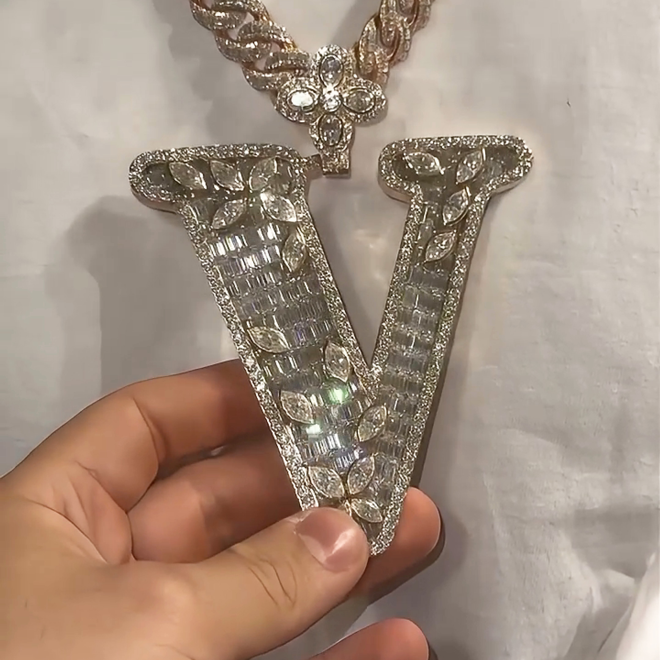 close up of V marquise letter pendant showing iced out stone detailing and bold hip hop inspired jewelry craftsmanship