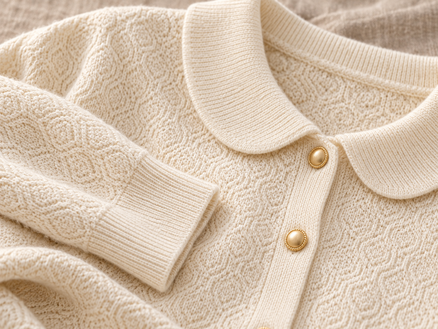 Macro close-up of ivory knit texture, collar edge and buttons