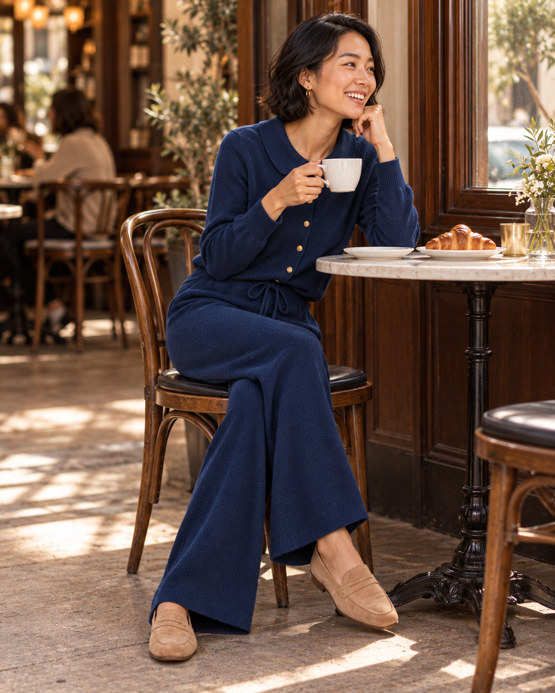 Smiling woman seated at a cafe in a navy knit set