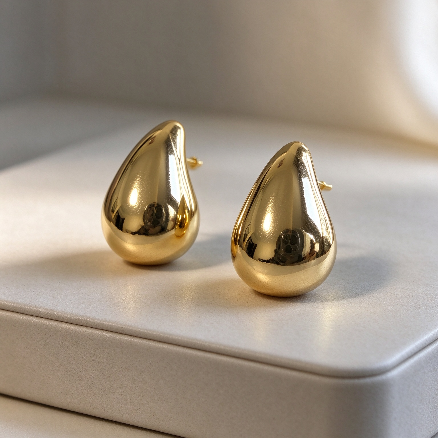 Gold teardrop statement earrings, polished gold drop design, luxury studio closeup, Bella Aurelia