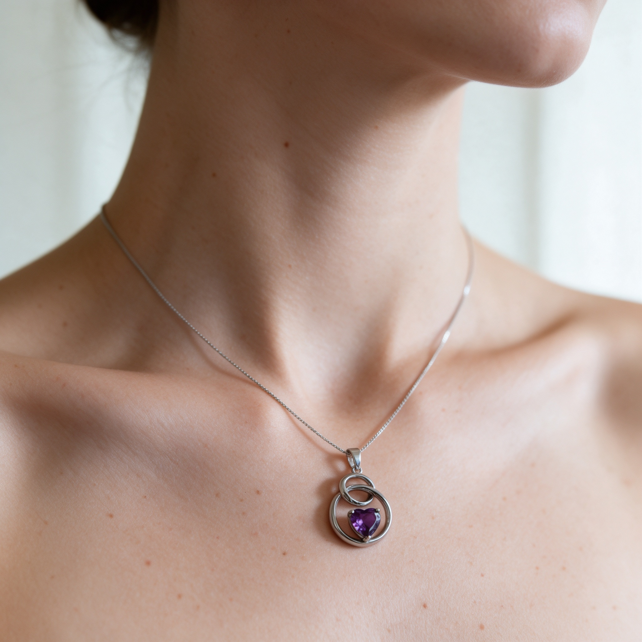 Natural skin tone model wearing purple heart silver pendant necklace, neck closeup jewelry photo