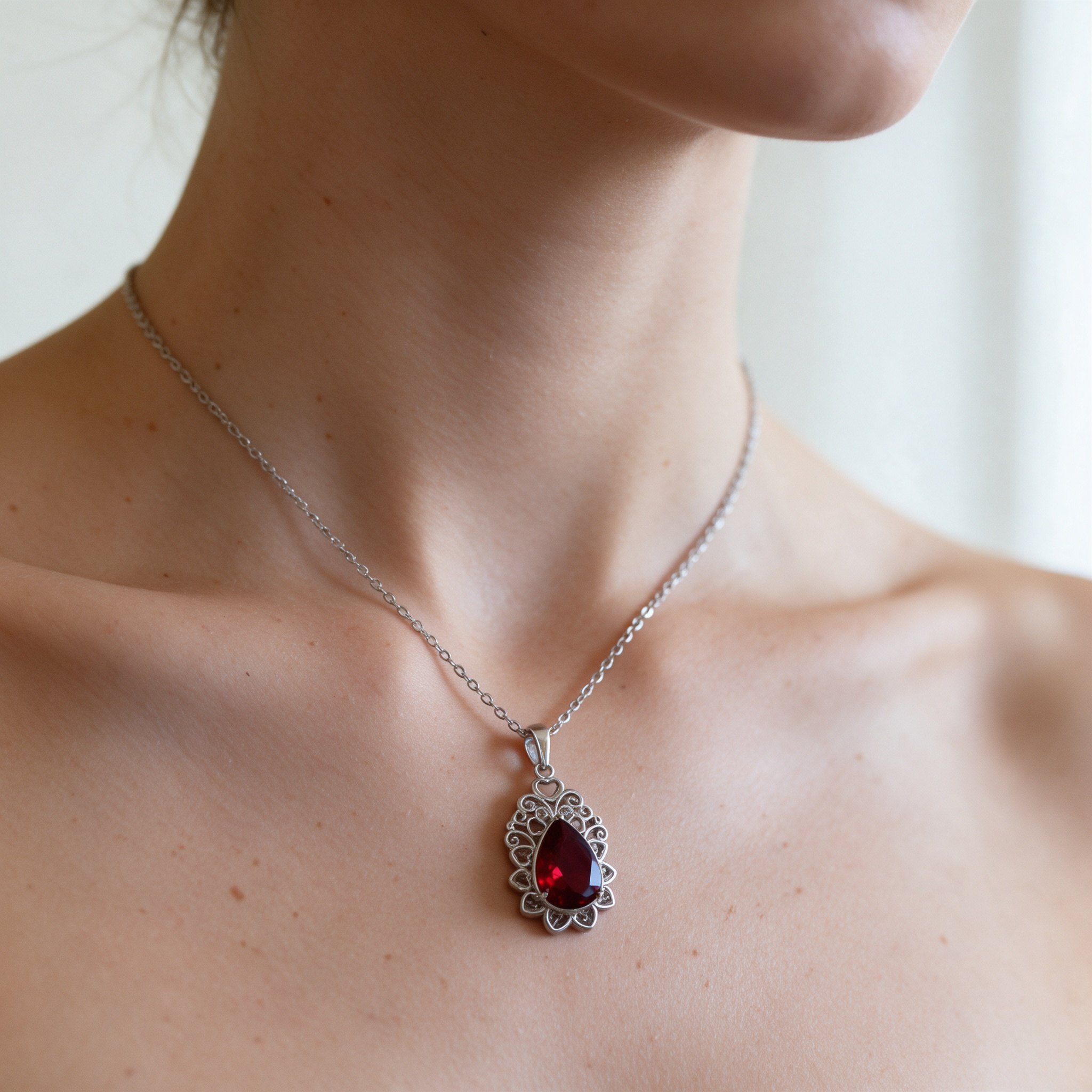 Natural skin tone model wearing red teardrop silver statement necklace, neck closeup jewelry photo
